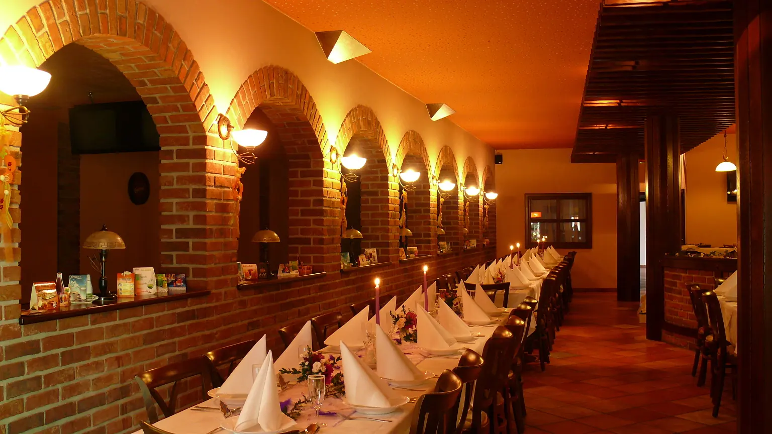 Restaurace večer – prostřené stoly pod cihlovými oblouky
